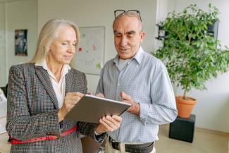 Professionally dressed man and woman looking at a tablet